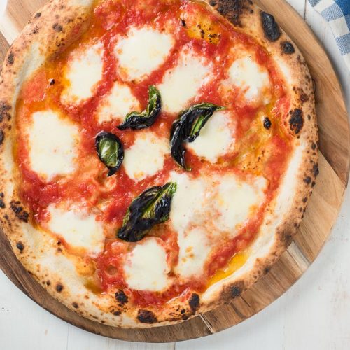 Pizza margherita on a cutting board from above.