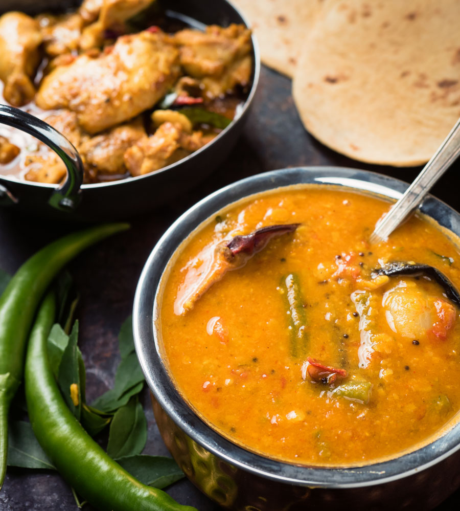 South Indian sambar in an Indian copper bowl with a spoon in it.