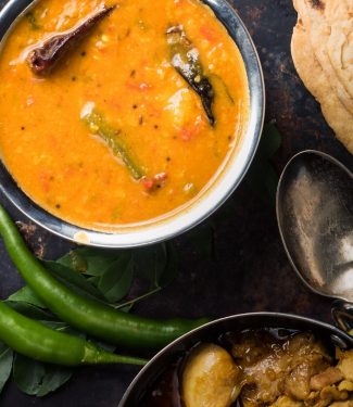 South Indian sambar in a metal bowl from above.