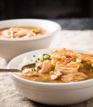 Spoon in a bowl of gumbo with chicken and sausage