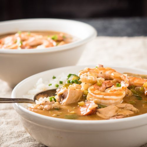 Spoon in a bowl of gumbo with chicken and sausage