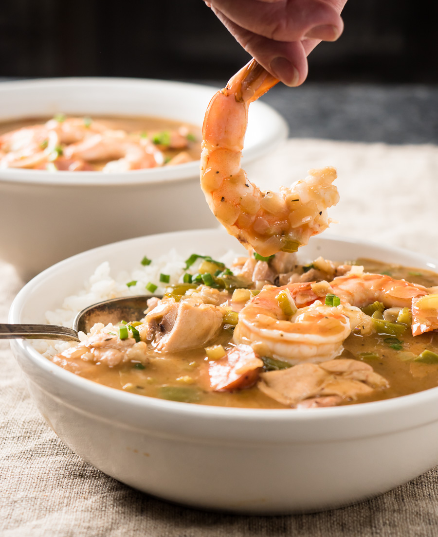 Picking up a shrimp from a bowl of gumbo.