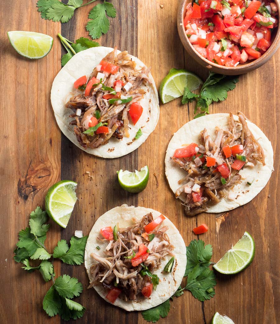 Carnitas street tacos on a wood board from above.