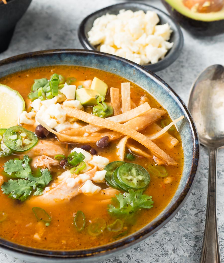 Chicken tortilla soup with spoon and cheese.