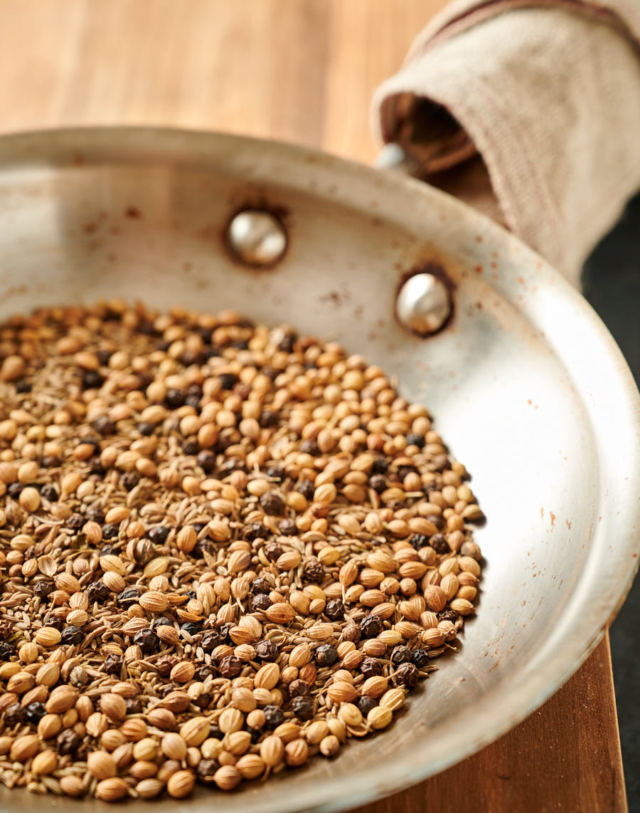 Whole spices for chaat masala toasting in a small skillet.