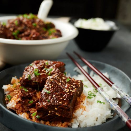 Korean beef stew with rice on a dark plate with chopsticks.