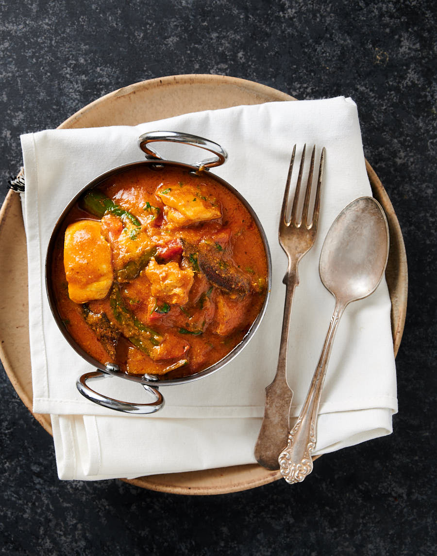 Bowl of chicken masala on a white napkin on a plate from above.