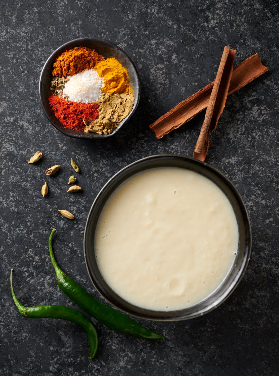 Moody overhead shot of onion paste and chicken masala spices.