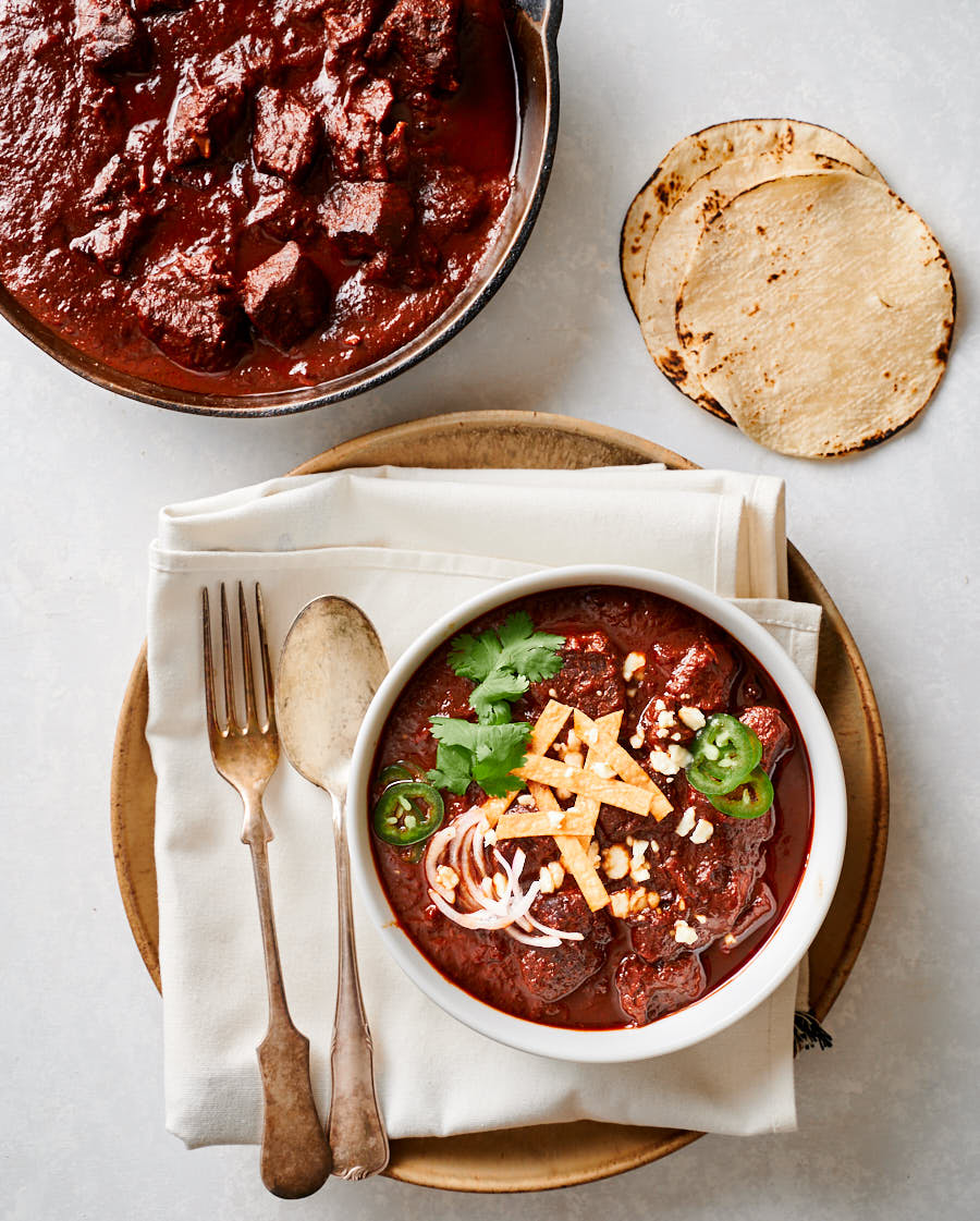 Chili colorado in a bowl with spoon and fork.