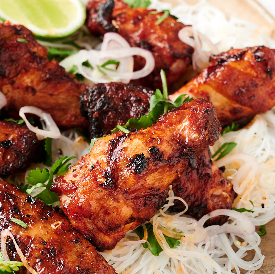 Close up of Korean chicken wings on rice noodles from the front.