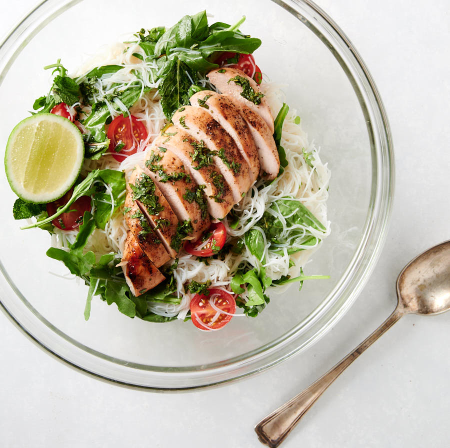 Thai chicken salad with rice noodles in a glass bowl from above.