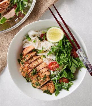 Thai chicken salad with rice noodles in a white bowl with chopsticks.