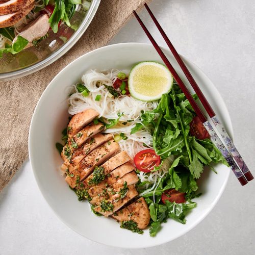 Thai chicken salad with rice noodles in a white bowl with chopsticks.