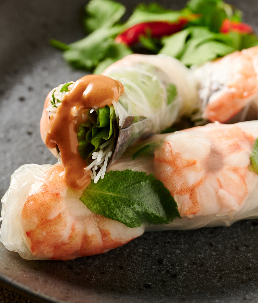 Cut Vietnamese spring roll with a drizzle of peanut sauce.