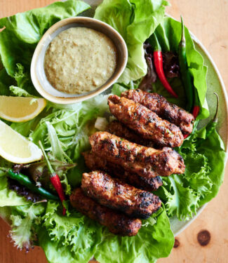 Indian seekh kebab on a plate with garnishes and dip from above.