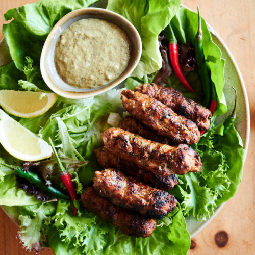 Indian seekh kebab on a plate with garnishes and dip from above.