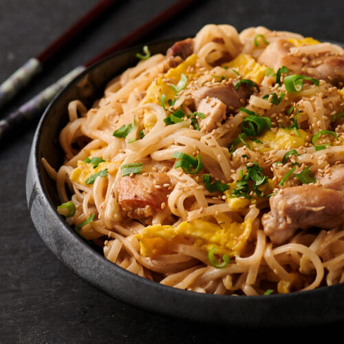 Thai sesame noodles on a black Asian plate.