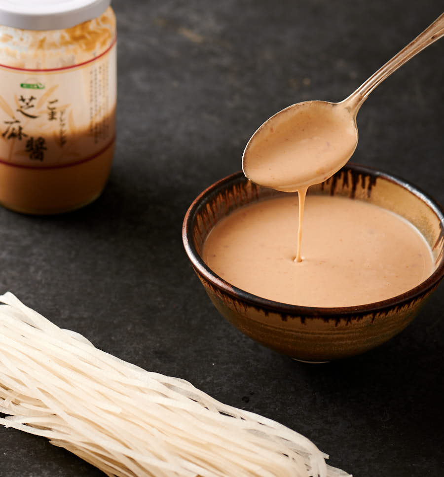 Sesame noodle sauce drizzled from a spoon