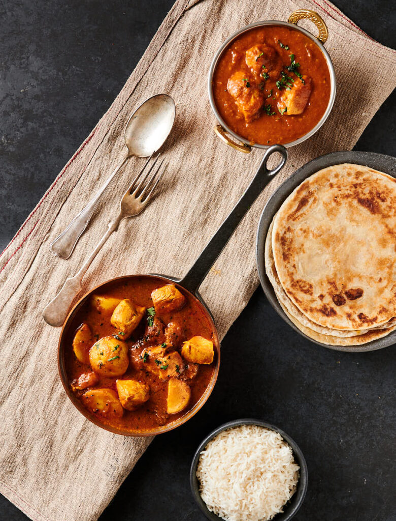 Bengali chicken curry with parathas and dhansak table scene from above.