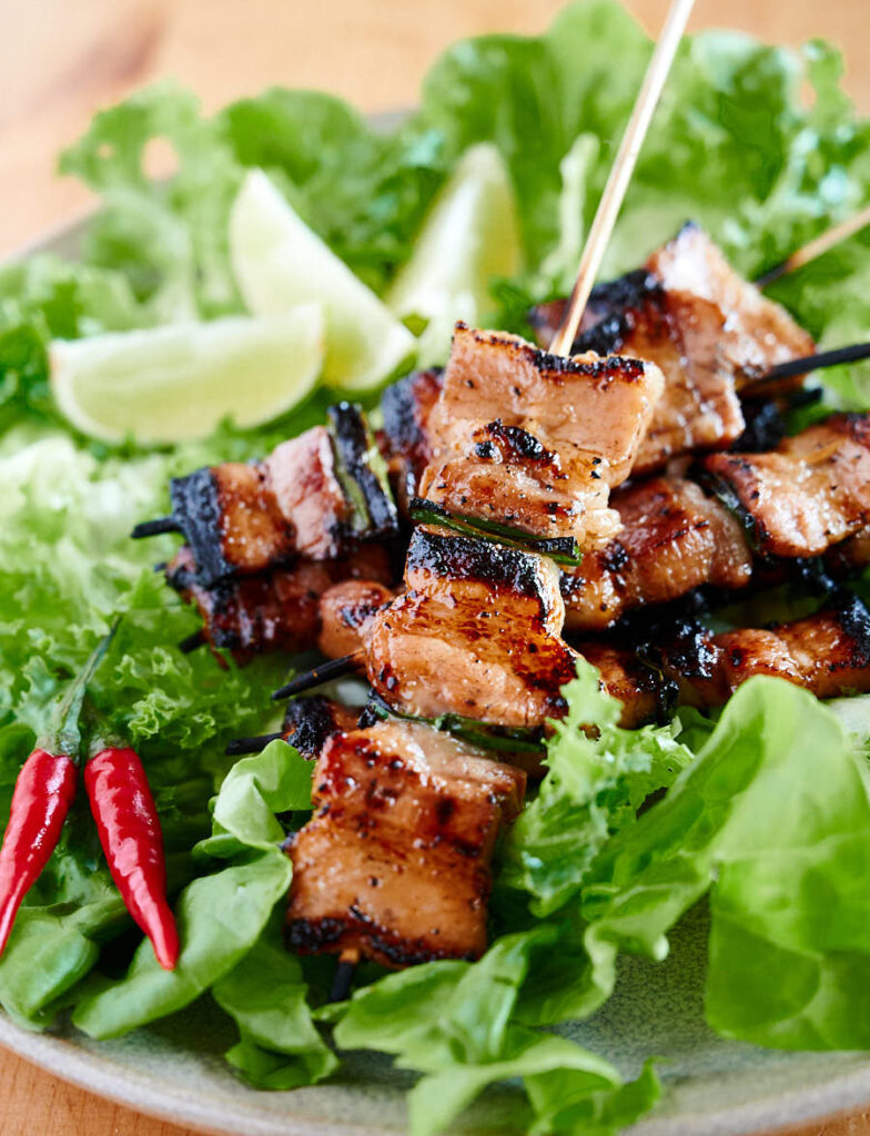 Closeup of grilled pork belly skewers from the front.