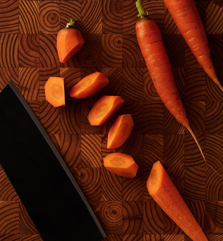 Rangari cut carrots and Japanese knife on a wood board from above.