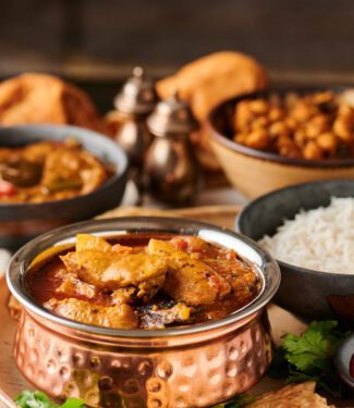 Murgir jhol table scene with rice and chickpeas from the front.