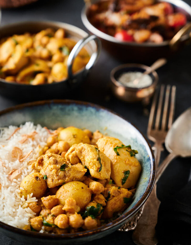 Chicken and chickpea curry in a bowl with rice from the front.