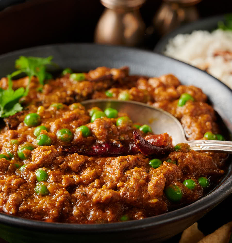 Close-up of keema matar with a spoon from the front.