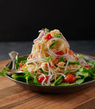 Mountain of som tam - papaya salad on a bed of greens from the front.