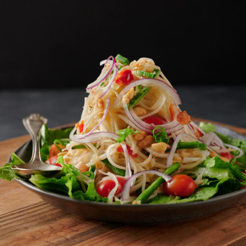 Mountain of som tam - papaya salad on a bed of greens from the front.