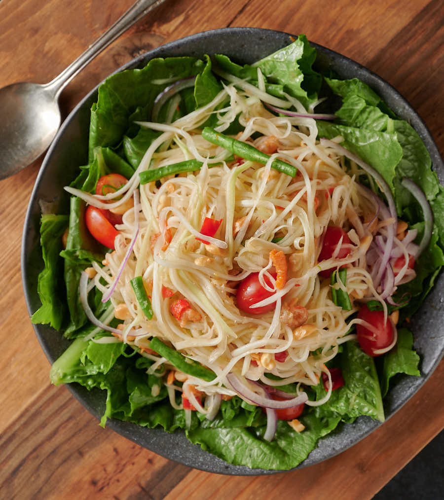 Pile of som tam on a bed of lettuce from above.