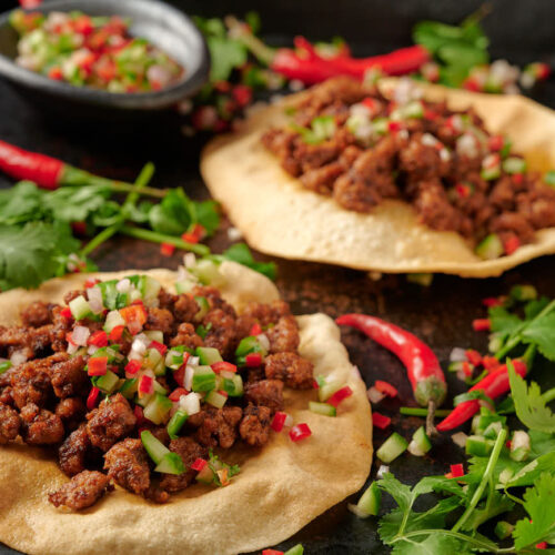 Two keema papadum and a bowl of kachumber salsa.