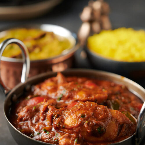 Indian green chili chicken curry with rice and dal palak from the front.