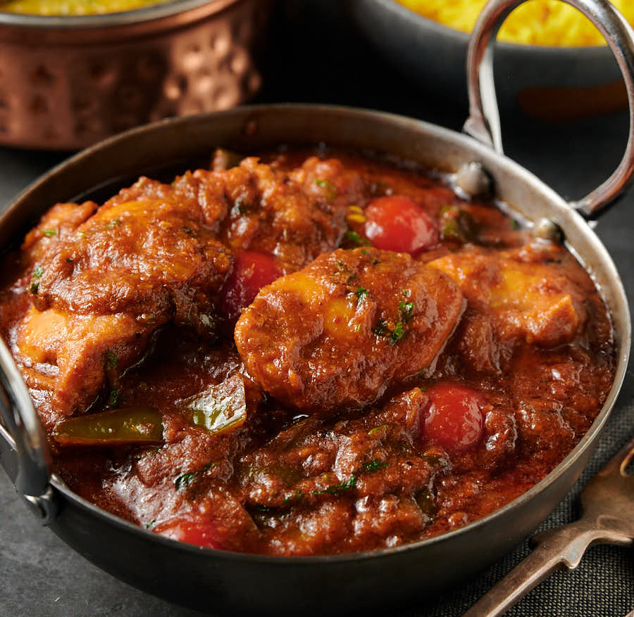 Close-up of green chili chicken curry in a carbon steel bowl from the front.