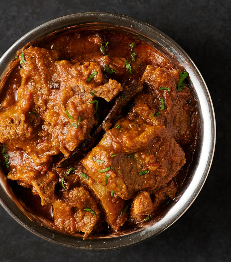 Indian hotel style lamb madras in a copper bowl from above.