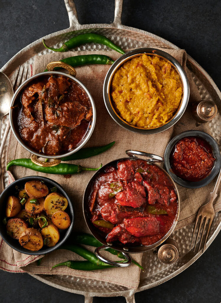 Naga chicken tikka curry, tarka dal, Ceylon chicken curry and chaat masala potatoes with green chilies.