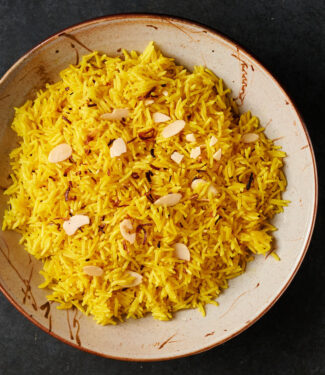 Bowl of turmeric coloured Indian restaurant style rice pilau from above.