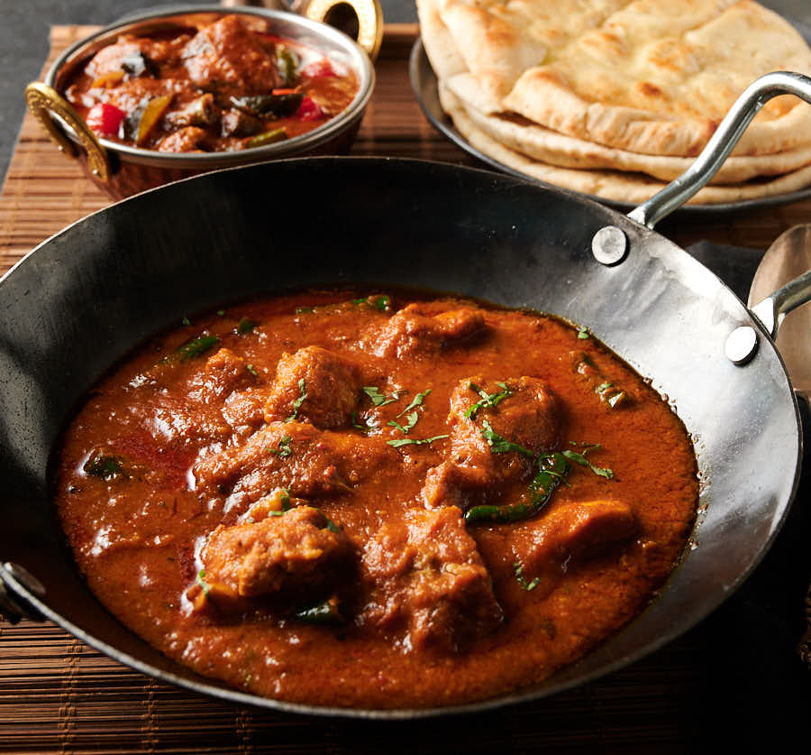 Achari chicken in a kadai (Indian wok) from the front.