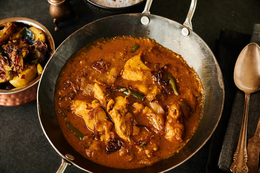 Chicken dopiaza in a carbon steel karai table view.