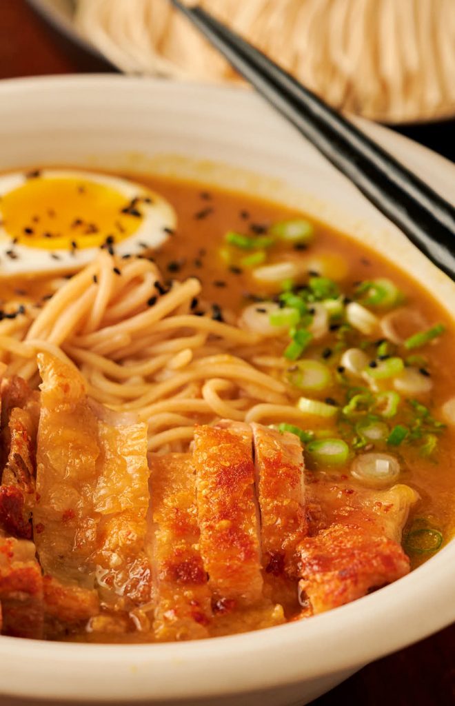 Closeup of crispy chicken in a bowl of curry ramen.