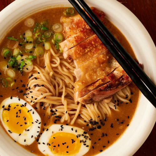 Closeup of bowl of curry chicken ramen garnished with black sesame seeds from above.