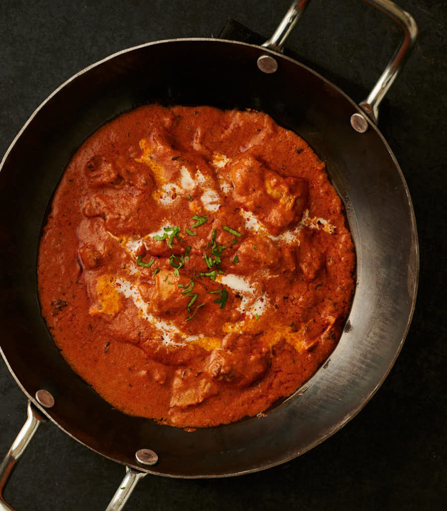 Hotel style butter chicken in a kadai from above.